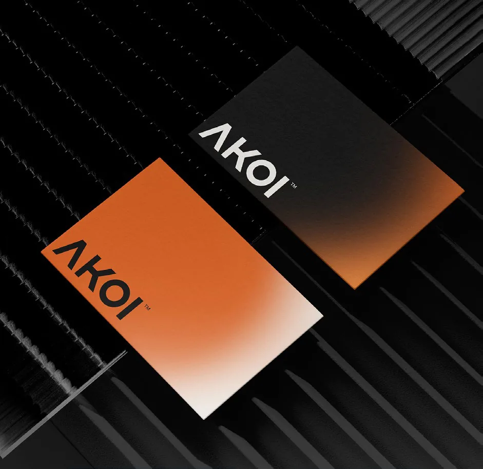Black and orange gradient Akoi business cards on a ribbed black surface